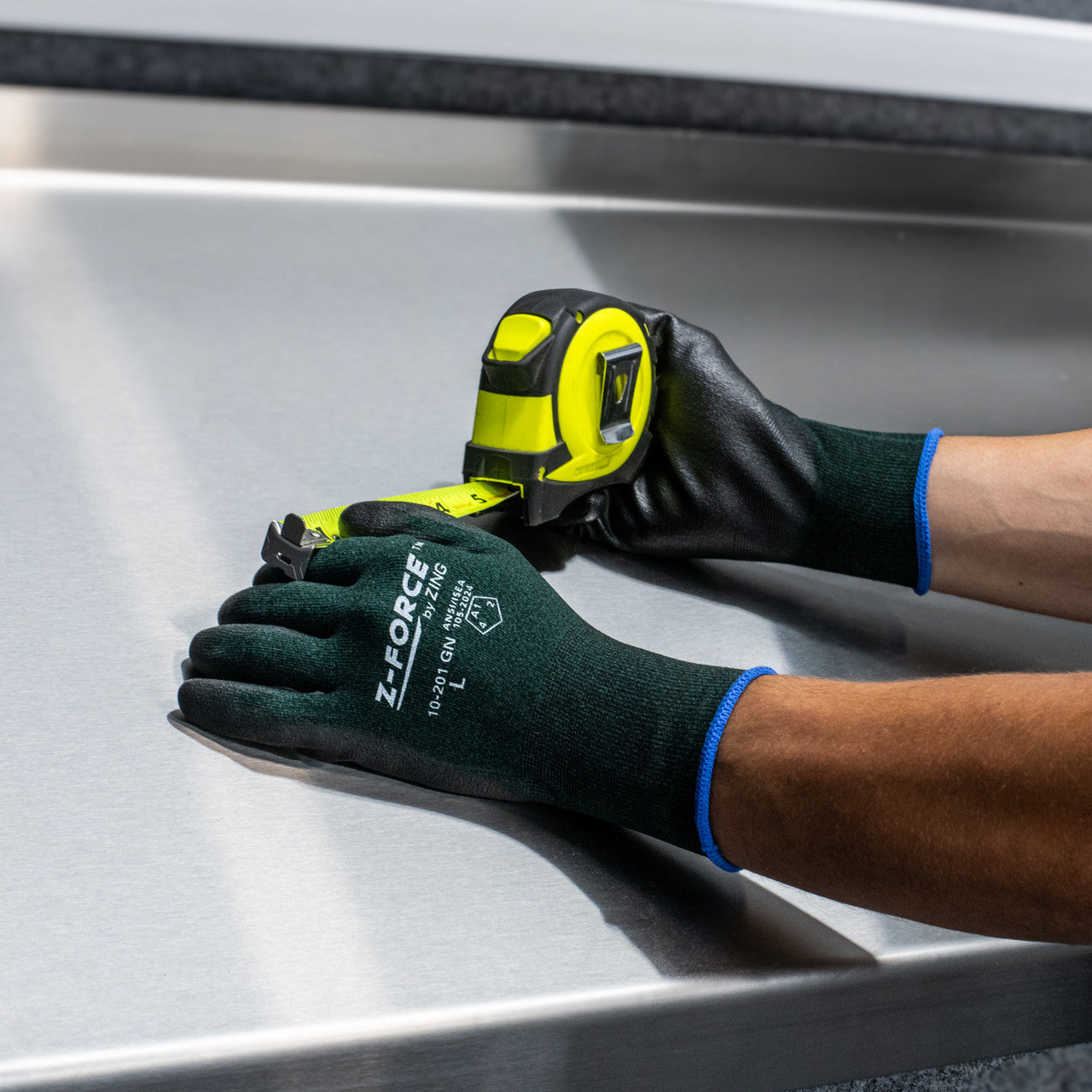 Worker wearing coated safety gloves while measuring sheet metal with tape measure